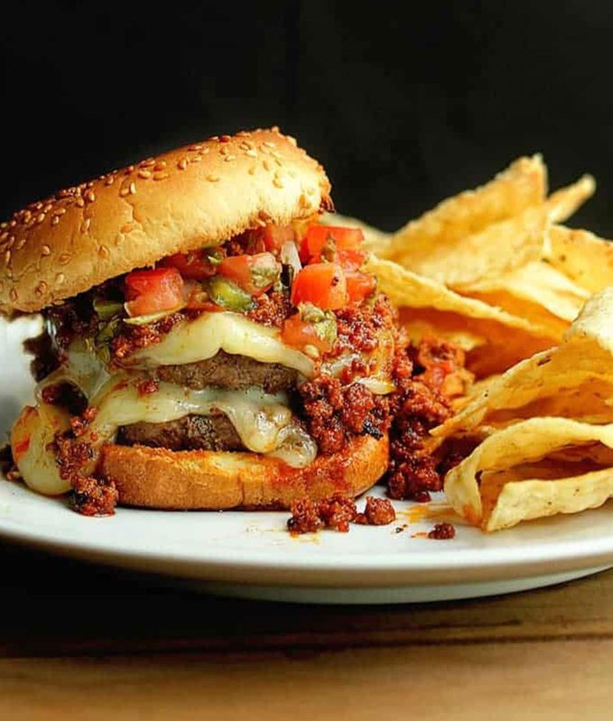 best burger recipes: latin-inspired burger topped with cheese and pico de gallo, on a plate with tortilla chips