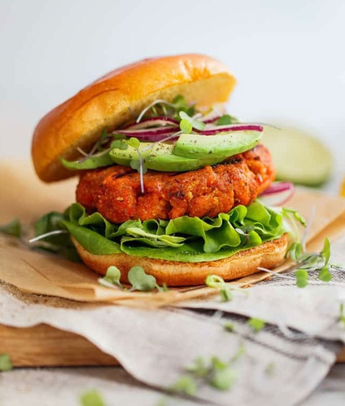 best burger recipes: mango-jerk salmon burger topped with greens and avocado, on a plate