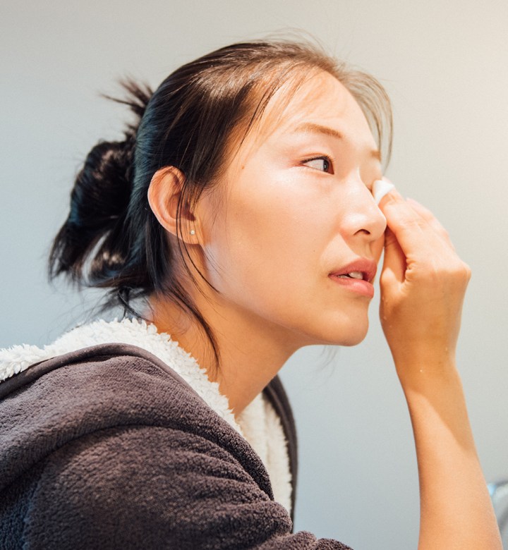 best makeup remover: a woman wiping off makeup from her eyes