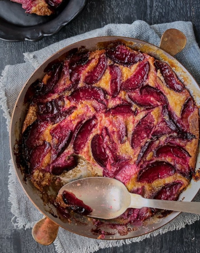 fun things to bake: aerial of plum clafoutis with a spoon that removed a scoop