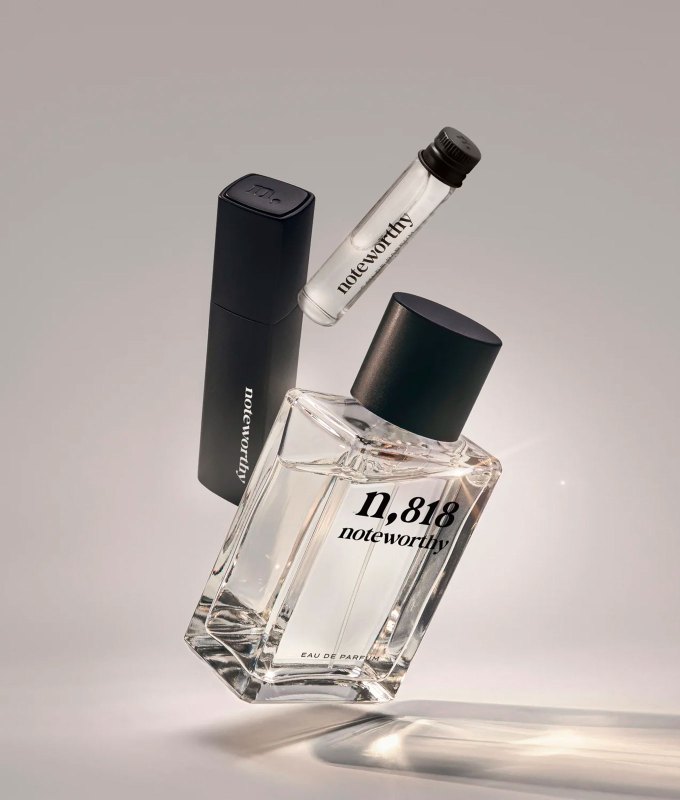 best-bedtime-perfume: A large clear bottle of perfume with a box and travel sized tube next to it. They seem to suspend in air in front of a gray background.