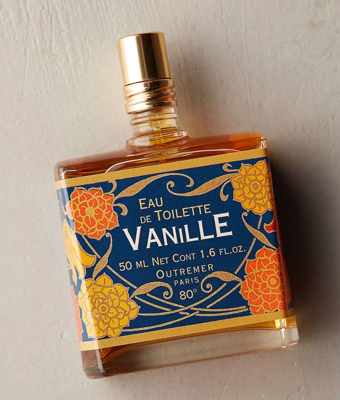 best-bedtime-perfume: A square perfume bottle with a blue, orange and yellow art-nouveau style design and a gold cap. There is an amber colored liquid inside the bottle.