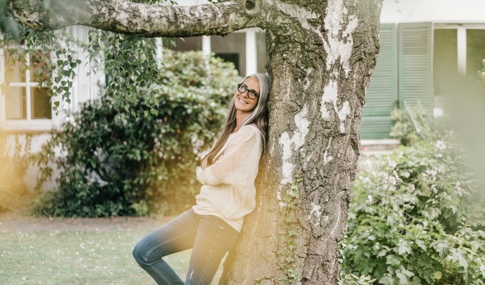 poses for pictures: woman leans on tree