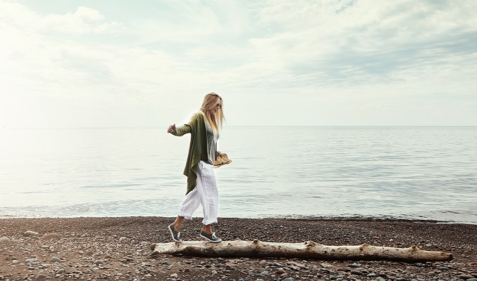 poses for pictures: woman walks on driftwood on the beach