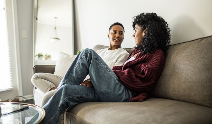 questions-for-couples: A multiracial lesbian couple at home relaxing on couch.